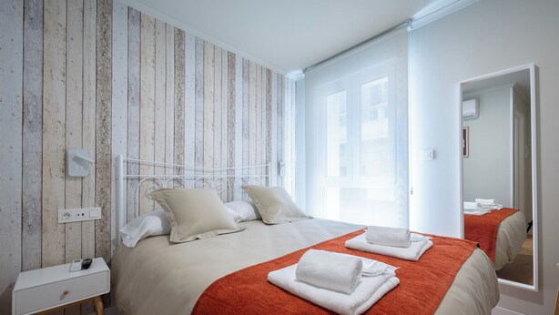 A hotel room with a bed, a bedside table, a power outlet, and a window. - Terra de Padrón Quality Rooms (Padron)
