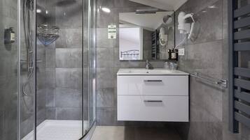 A modern bathroom with a glass-enclosed shower, a white vanity with a mirror, and a towel rack.