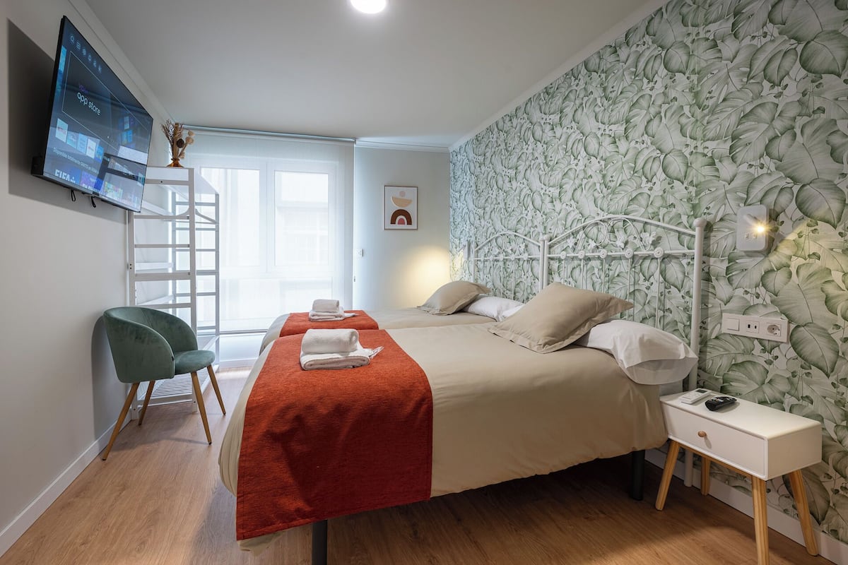 Una habitación de hotel con una cama, un escritorio, una silla y un televisor instalado en la pared.