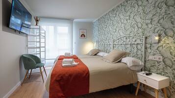 Una habitación de hotel con una cama, un escritorio, una silla y un televisor instalado en la pared.