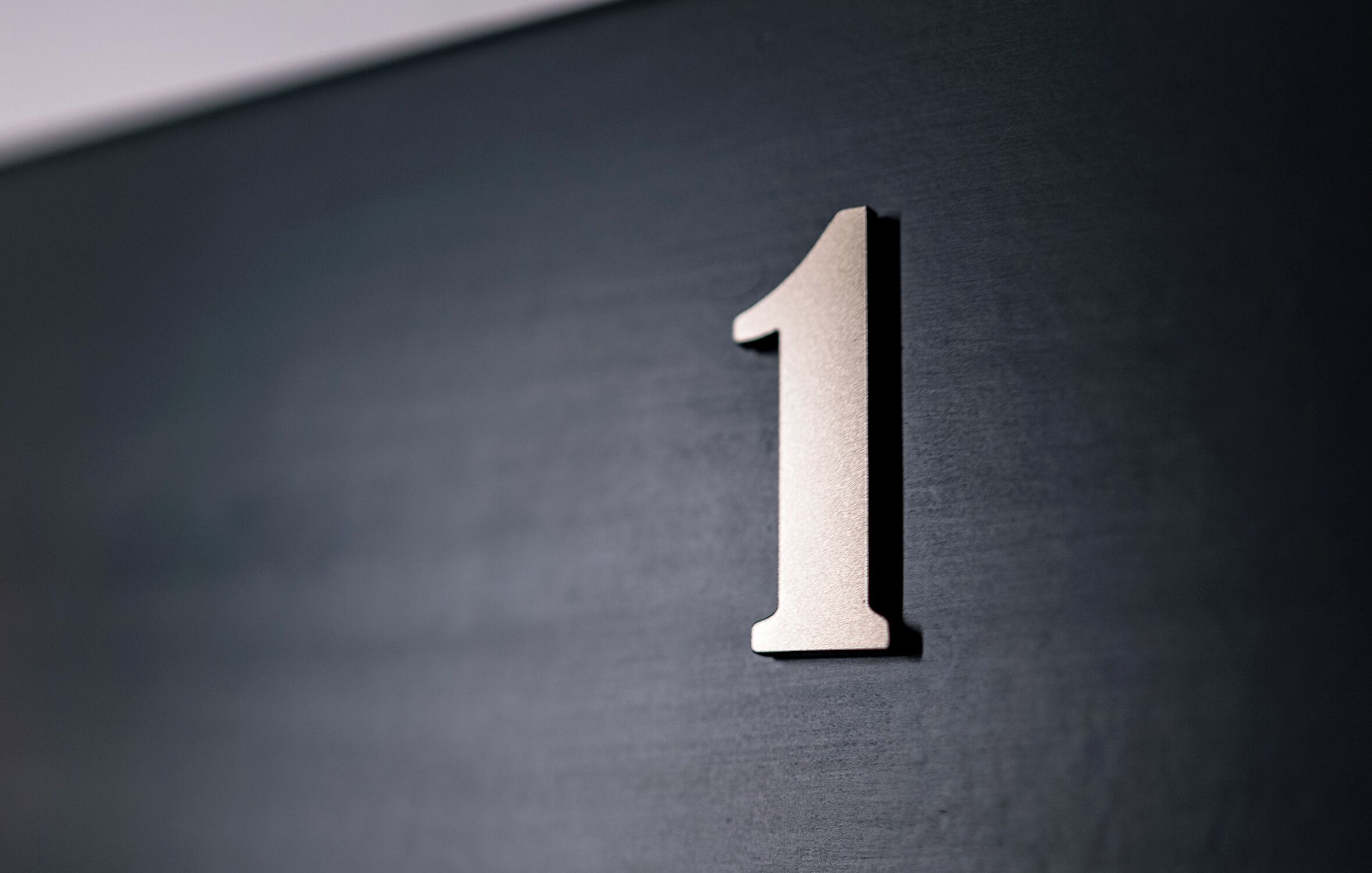 A close-up of a metallic number '1' on a dark surface.