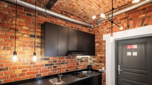 A modern kitchen with exposed brick walls, stainless steel appliances, and pendant lighting.