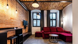A modern living room with a brick wall, a red sectional sofa, a round coffee table, and a TV mounted on the wall.