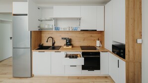 A modern kitchen with white cabinets, a wooden countertop, a built-in oven, and a dishwasher.