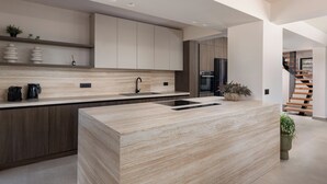 Una cocina moderna con una isla central, armarios empotrados y una escalera al fondo.