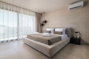 A modern hotel bedroom with a large bed, a nightstand, an air conditioning unit, and a view of the city.