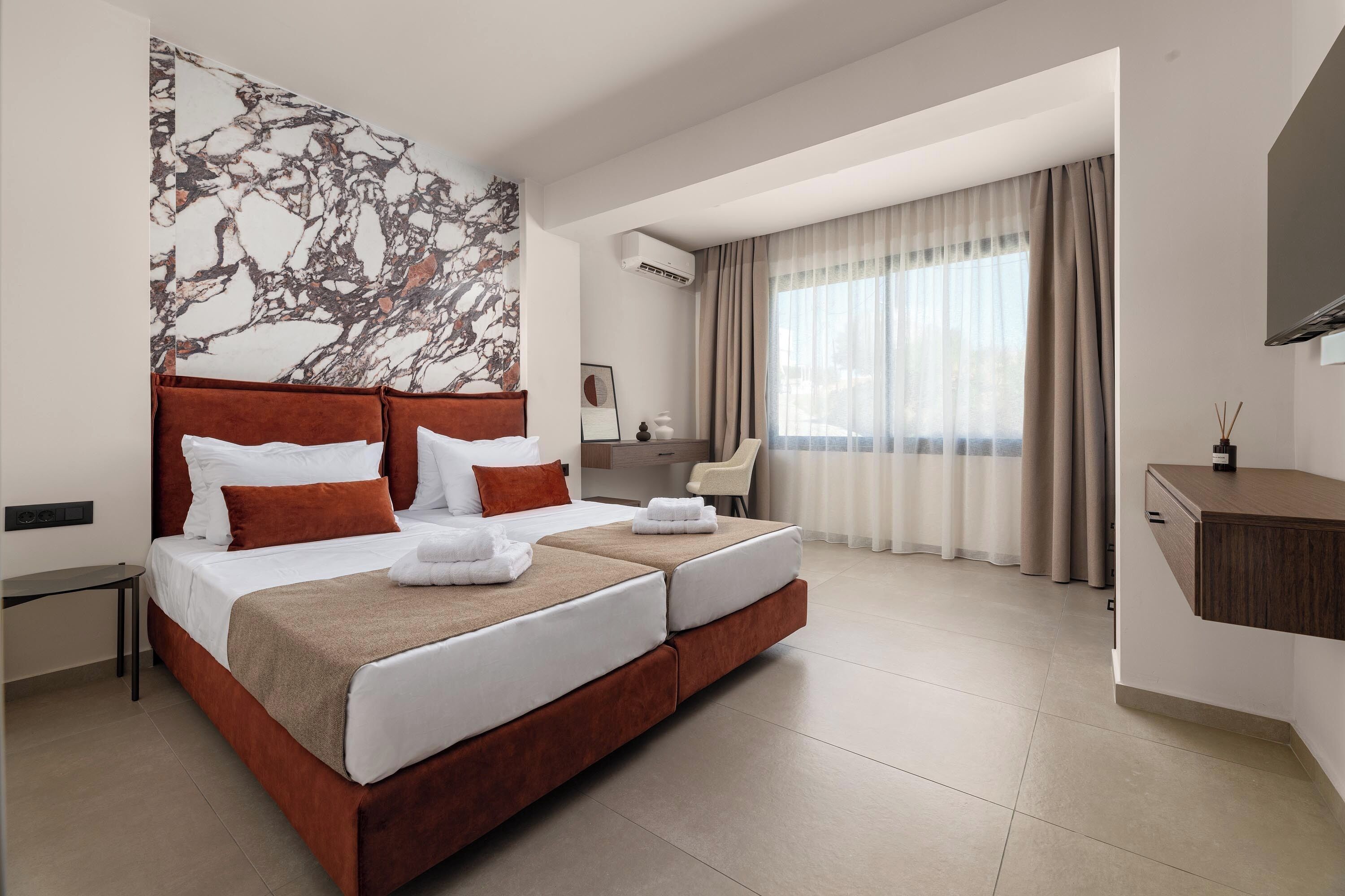 Een moderne hotelkamer met een groot bed, een bureau, een stoel en een groot raam met gordijnen.