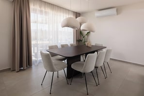 A modern dining area with a dark wooden table, six chairs, and three pendant lights.