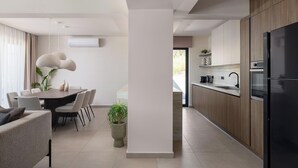 Una cocina moderna con un refrigerador negro, armarios de madera y un comedor con mesa y sillas.