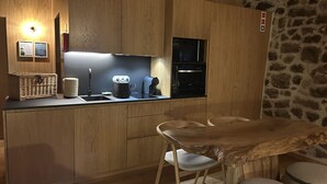 A compact kitchen with wooden cabinets, a built-in microwave, and a coffee maker. There is a small dining area with a wooden table and two chairs. - an accommodation unit in the form of a studio T1 with 39m2 (Sortelha)
