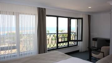 Habitación de hotel con una cama grande, un escritorio y vistas al mar y a edificios.