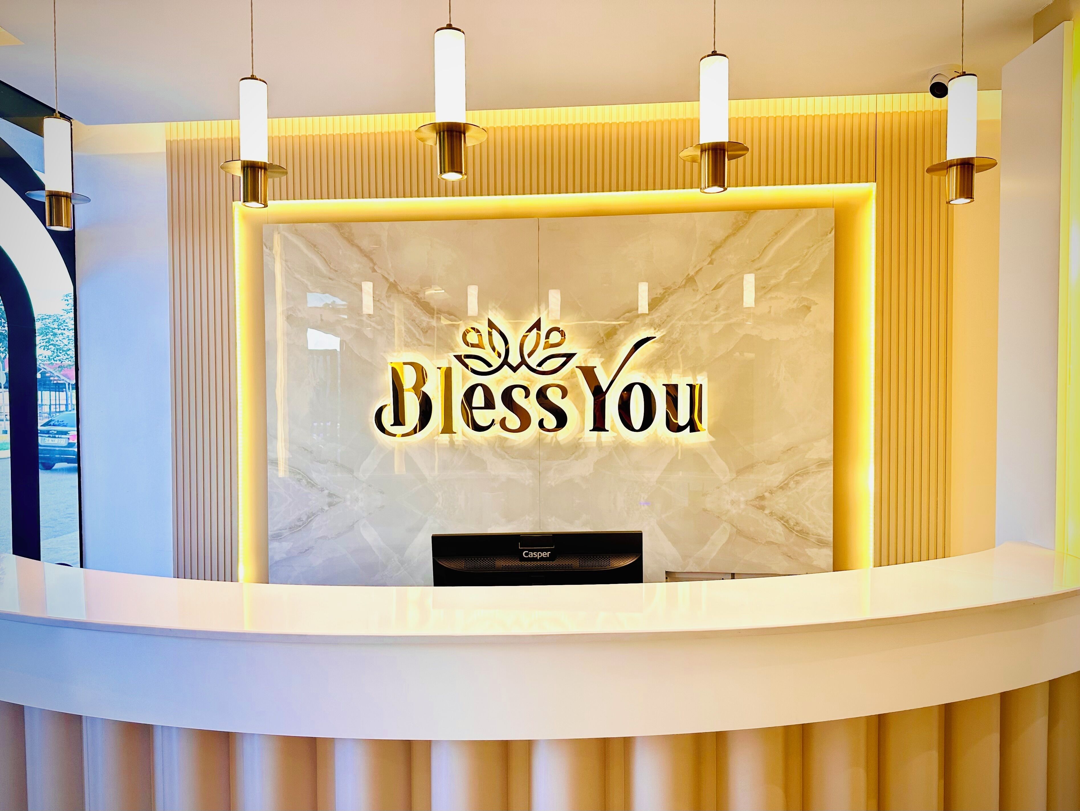 A reception desk with a 'Bless You' sign, a speaker, and a modern design with vertical paneling.