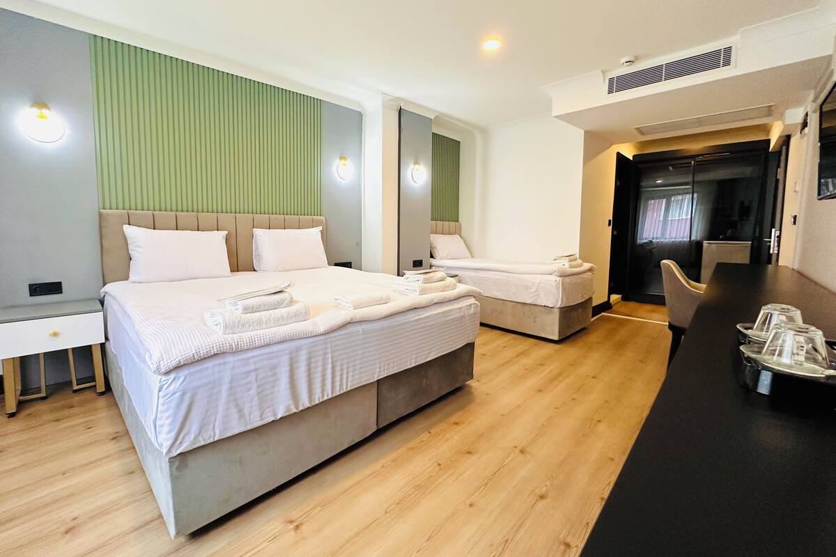 Ein modernes Hotelzimmer mit einem großen Bett, einem kleineren Bett, einem Schreibtisch und einer Sitzecke.