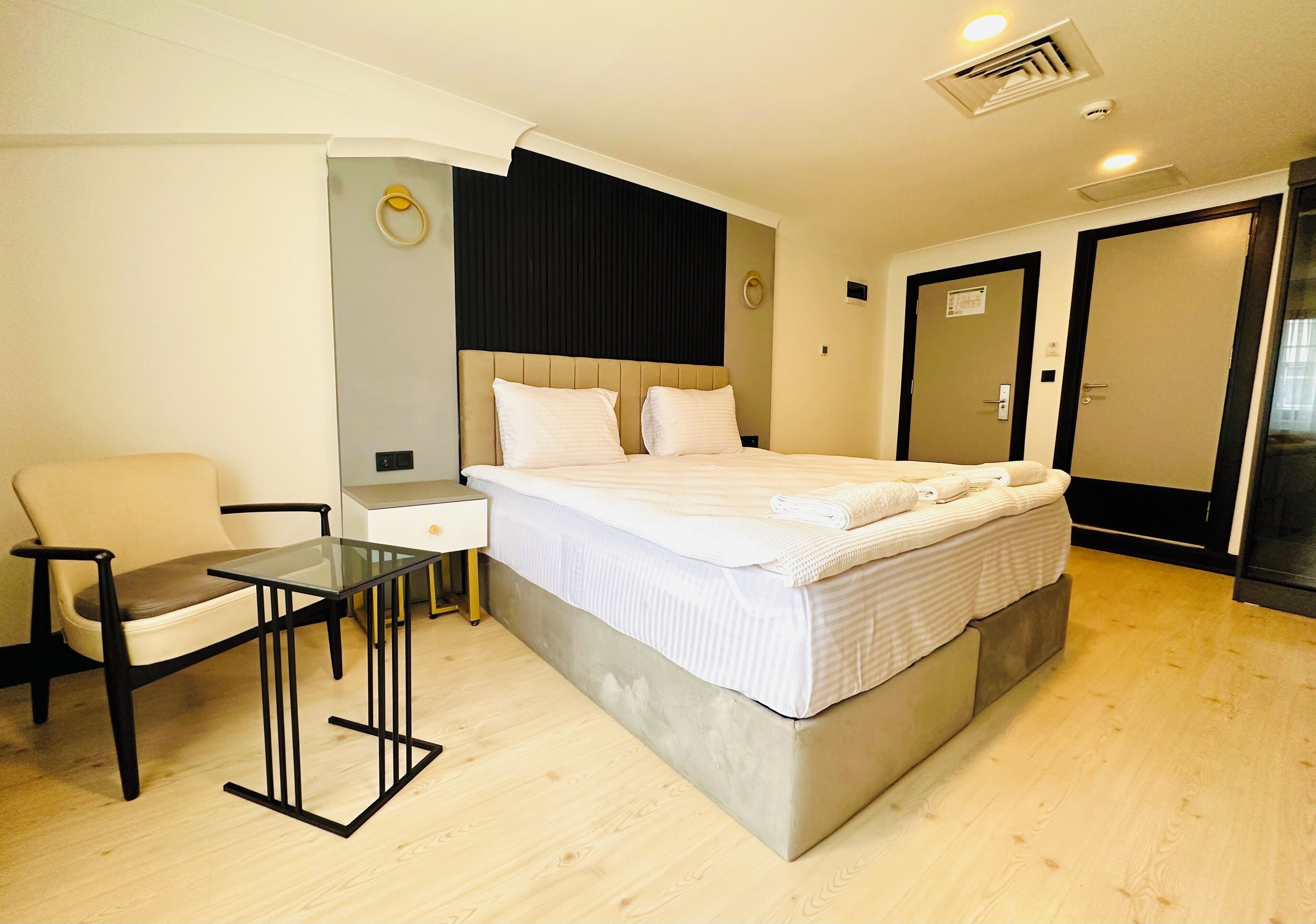 Une chambre d’hôtel moderne avec un grand lit, une table en verre, une chaise et un bureau.