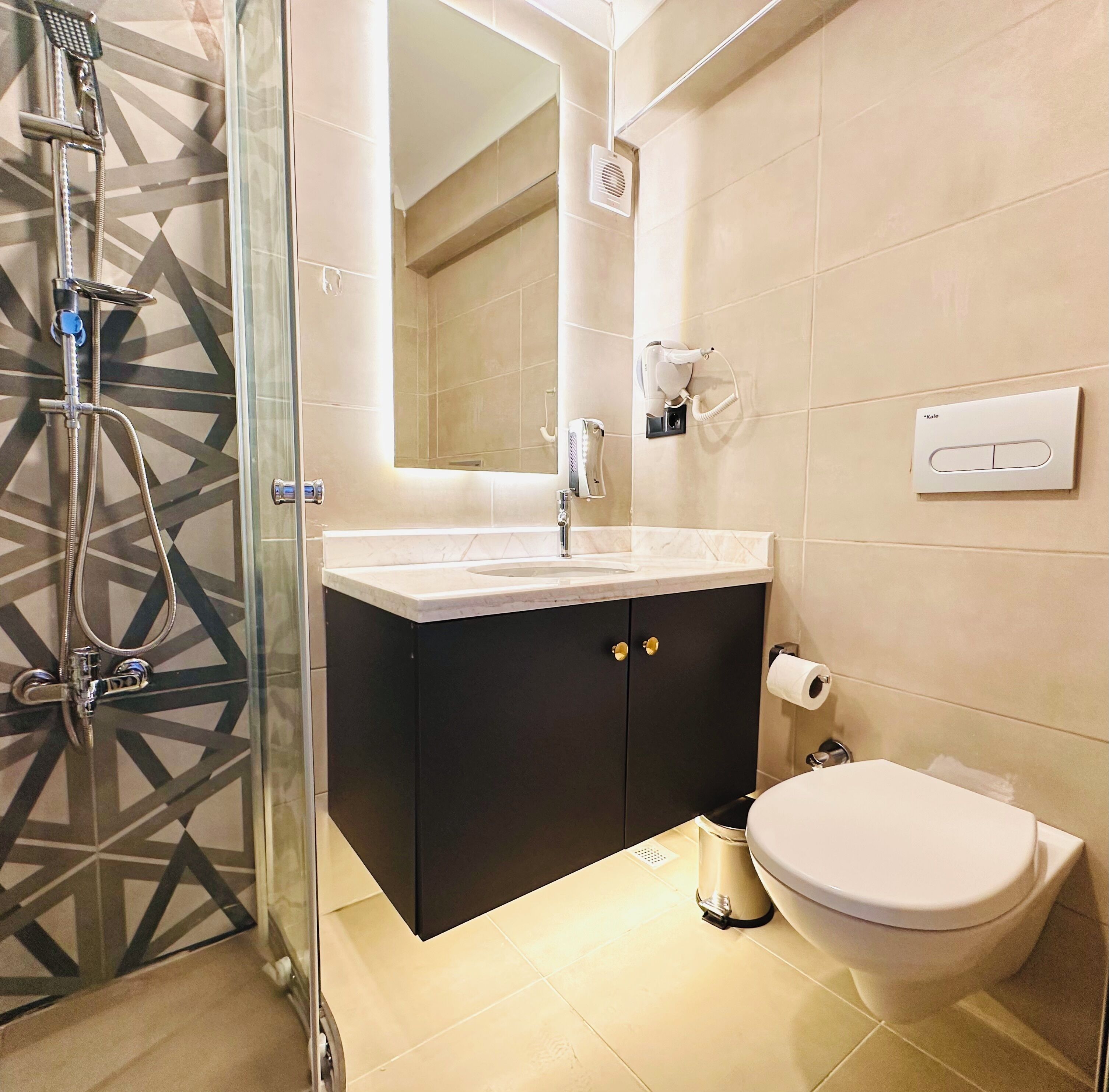 Une salle de bain moderne avec une douche à parois de verre, un meuble-lavabo avec un évier, des toilettes et un miroir au-dessus du meuble-lavabo.