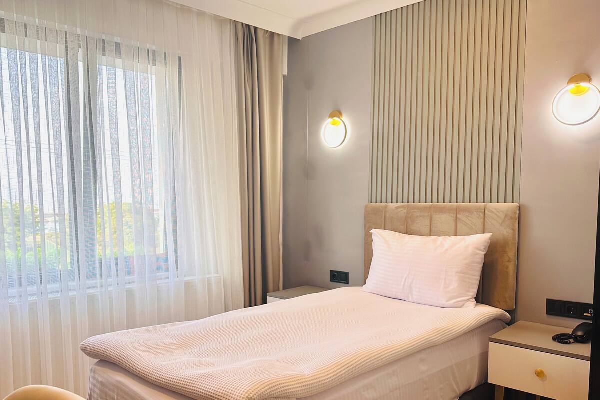 Ein modernes Hotelzimmer mit Bett, Nachttischen, einem Schreibtisch und einem Sessel.