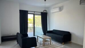 A modern living room with a black sofa, a wooden coffee table, and a patterned rug. - Cozy 3 Bedroom Villa Close to the Beach (Limassol)