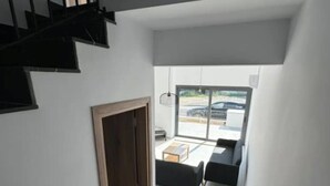 A modern interior with a staircase, a seating area with sofas, and a view through a glass door. - Cozy 3 Bedroom Villa Close to the Beach (Limassol)