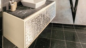 A modern bathroom with a large mirror, a vessel sink, and a black and white patterned vanity.