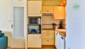 A compact kitchen with a microwave, oven, and a coffee maker. - La Goëlette 30 Les mouettes (Saint-Hilaire-de-Riez)