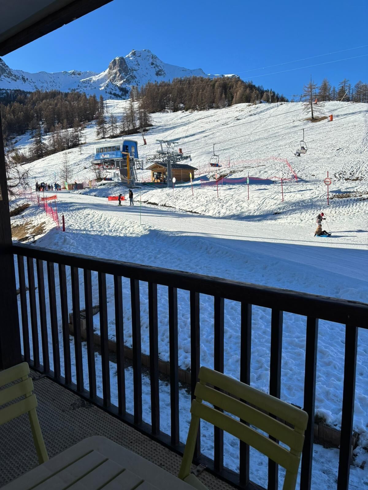 Une piste de ski enneigée, avec un télésiège, un chalet de ski et une montagne en arrière-plan.