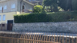 Un edificio de varios pisos con paredes de piedra, balcones y una cerca de piedra en primer plano.