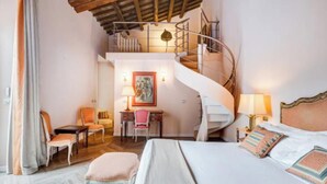 Une chambre à coucher avec un grand lit, un bureau, une chaise, une petite table et un escalier en colimaçon.