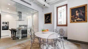 Une cuisine moderne avec un coin repas vitré, un four à micro-ondes et une cuisinière. Deux tableaux encadrés ornent le mur.