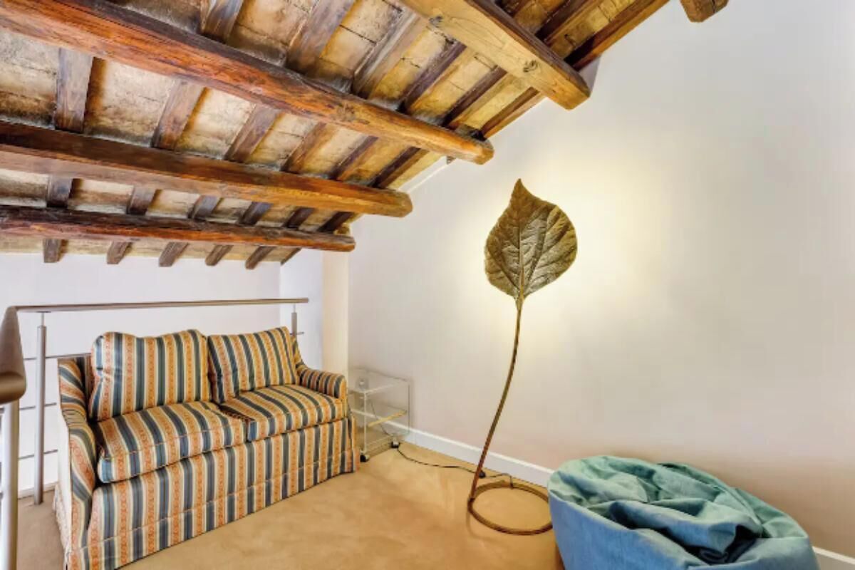 Una habitación acogedora con un sofá a rayas, una lámpara de pie con forma de hoja y un sillón de peluche azul.