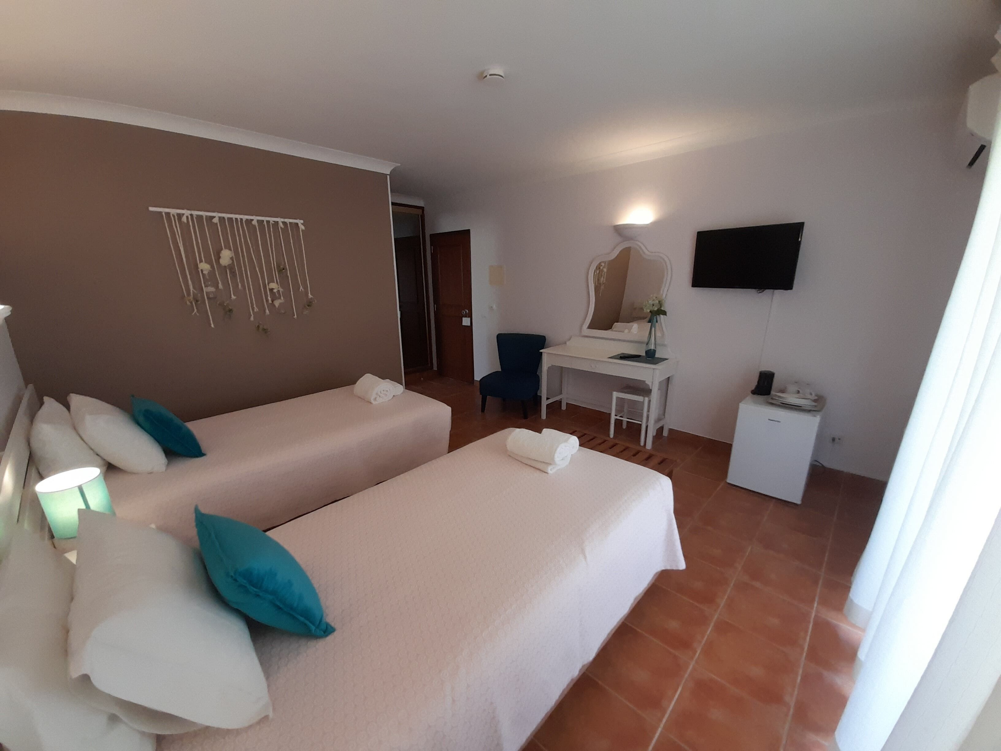 A hotel room with two beds, a desk, a chair, a TV, and a mirror.