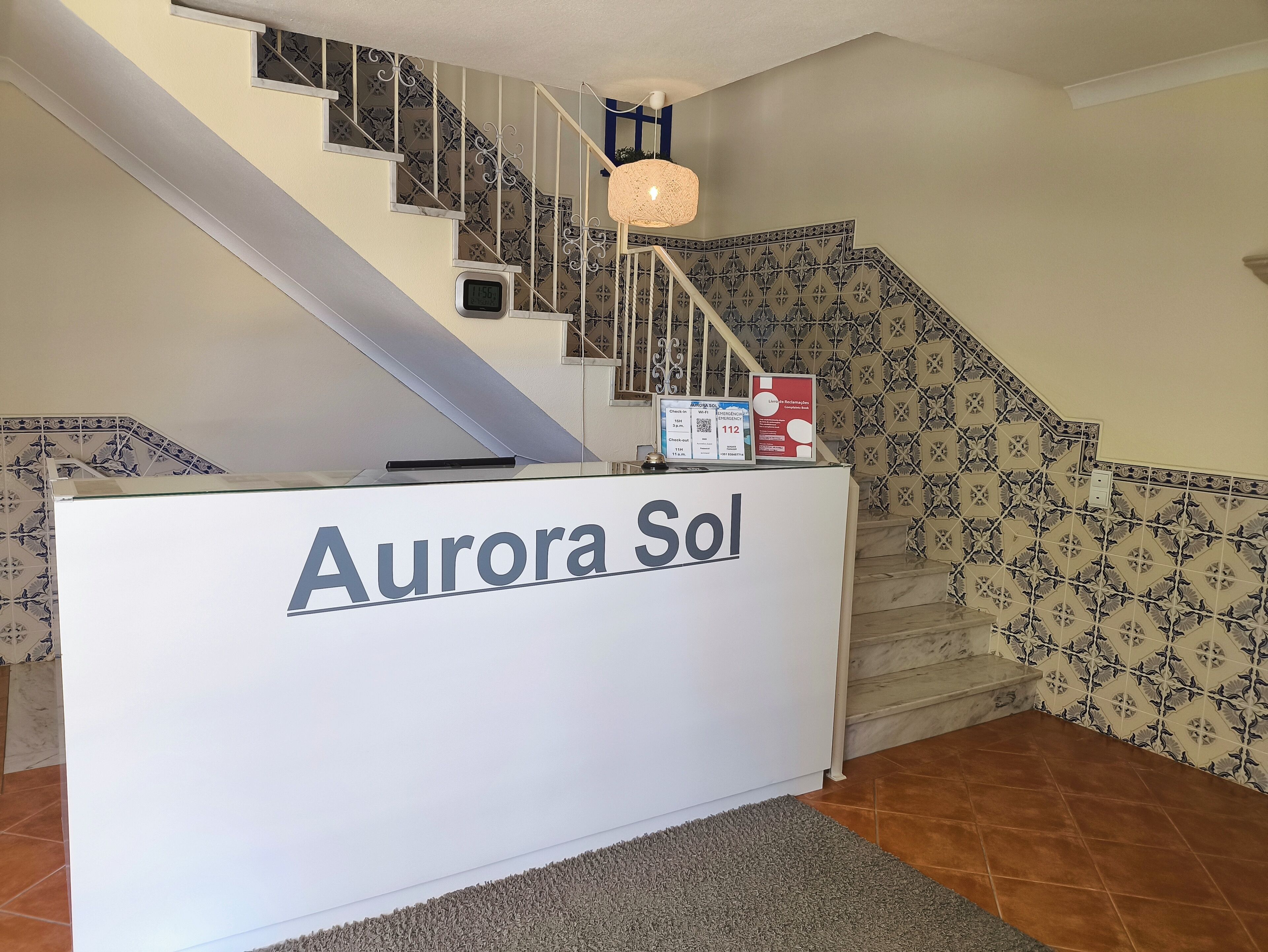 A reception desk labeled 'Aurora Sol' with a staircase in the background.