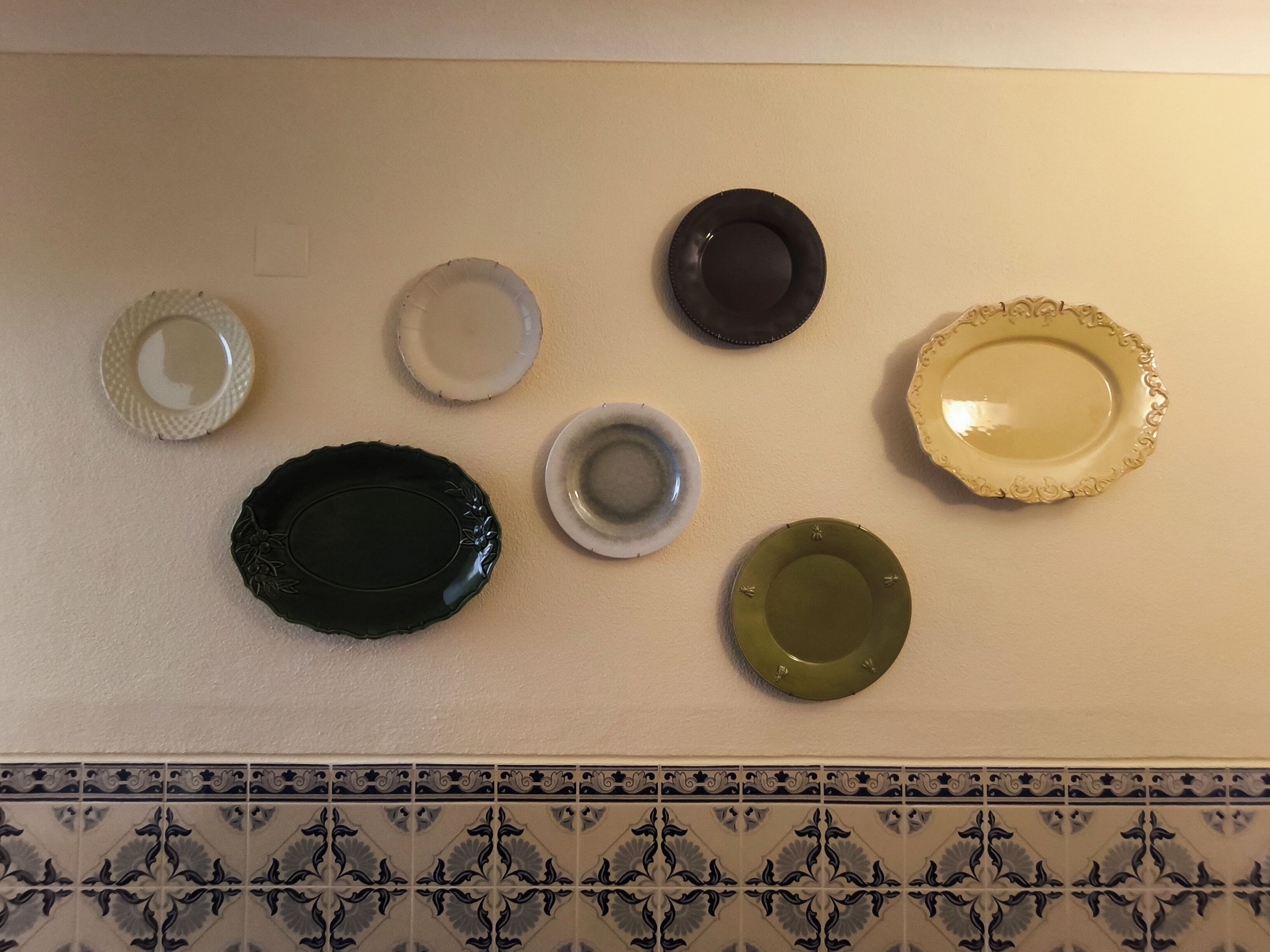 A wall with seven plates arranged in a row.