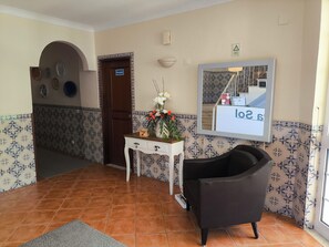 A hotel lobby with a reception desk, a black armchair, a door labeled 'Privado,' and a wall-mounted sign.