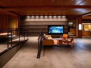Una sala de estar moderna con un televisor de pantalla plana grande, un sofá y una mesa de centro.