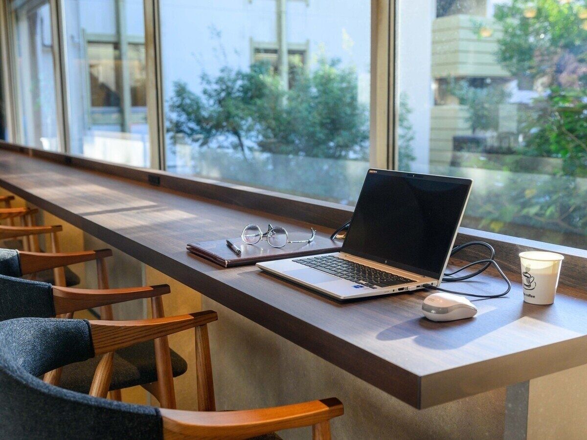A modern workspace with a laptop, glasses, and a coffee cup on a wooden table.