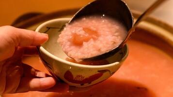 Un bol de riz crémeux rose, accompagné d’une cuillère.