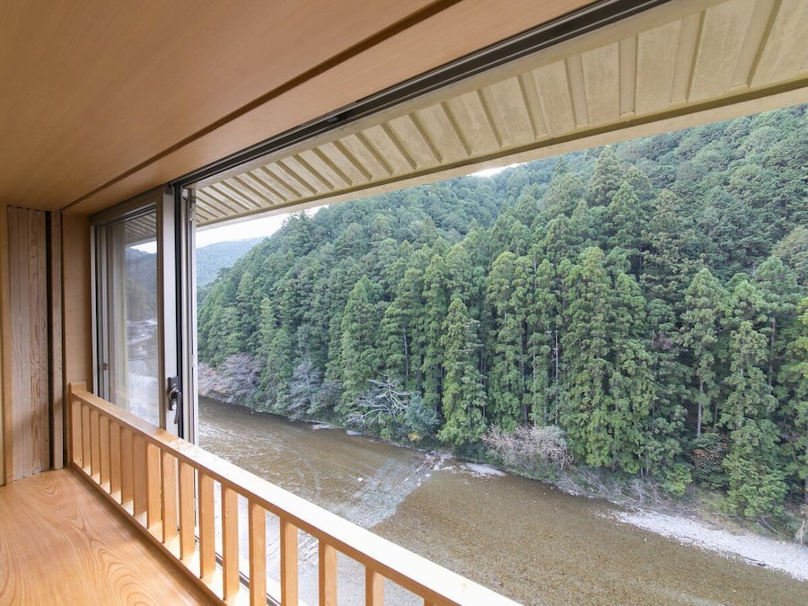 A room with a view of a river and forest.