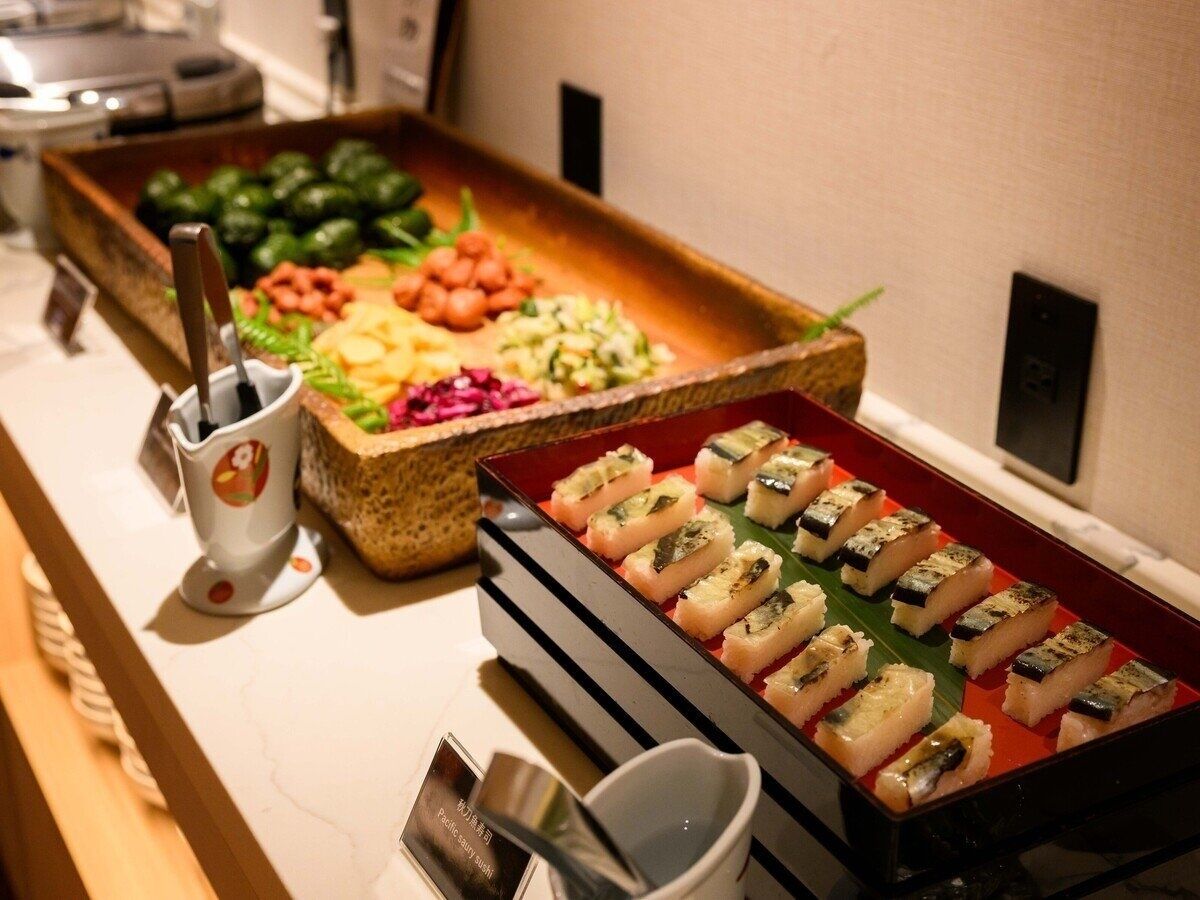 A buffet with various dishes, including sushi, vegetables, and a drink station.