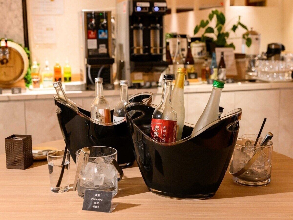 A bar area with various bottles and glasses, including a bottle of red wine, ice cubes, and a black bucket.