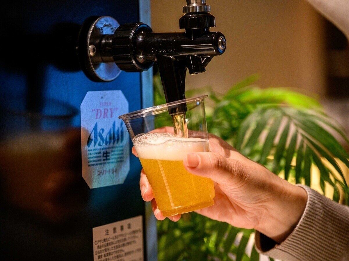 A hand holding a glass receiving beer from a tap.
