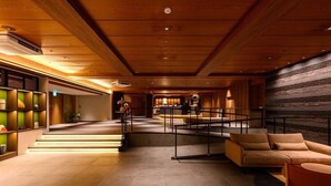 A spacious lobby with a wooden ceiling, a reception desk, a sofa, and a staircase leading to upper floors. - Sansuikan Kawayu Midoriya (Tanabe)