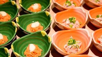A variety of small, square-shaped dishes with different colored rims, each containing a similar food item topped with a white substance and garnished with green onions.