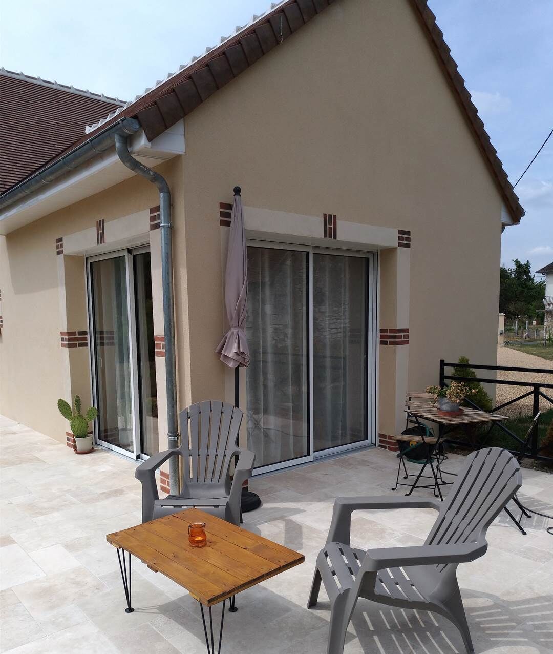 Eine Außenpatio mit Tisch, Stühlen, einer Schiebetür und einem Blumentopf.