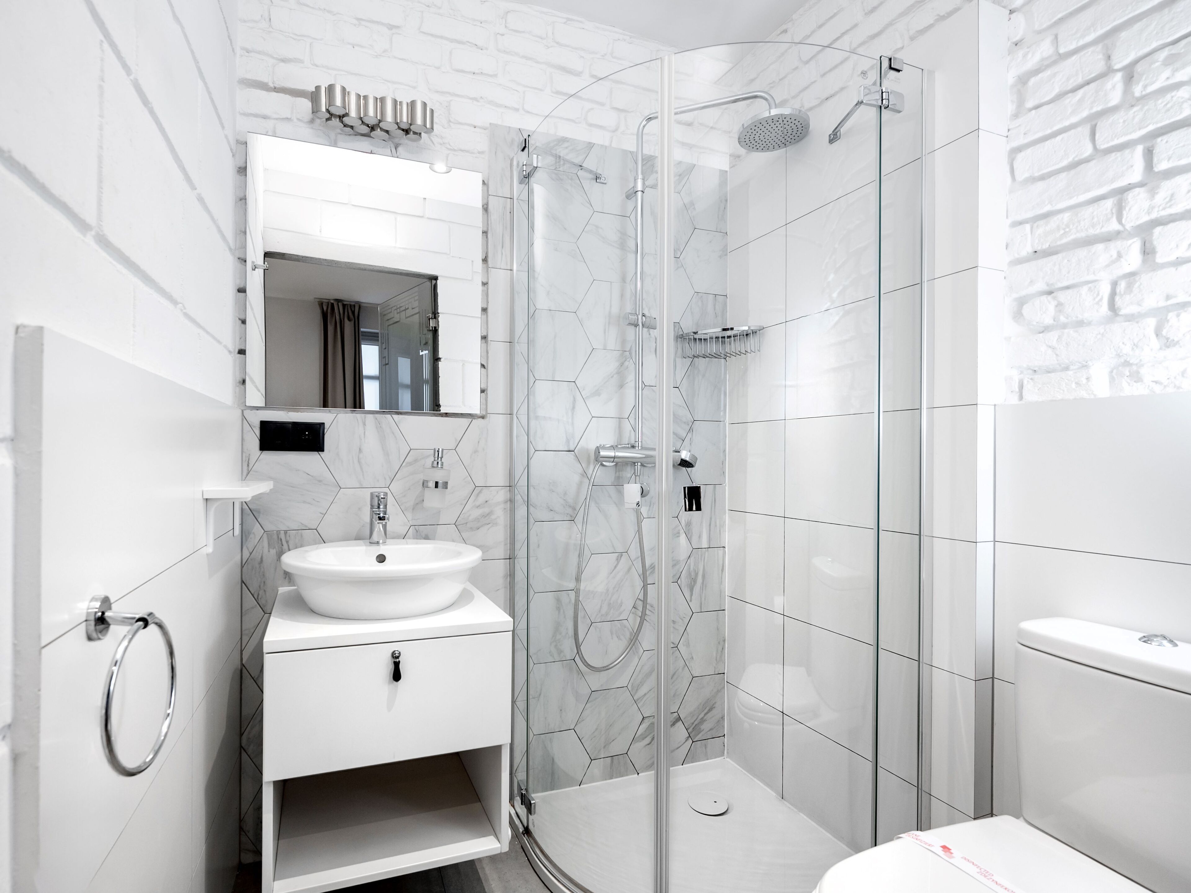 A modern bathroom with a glass-enclosed shower, a white sink, and a mirror above the sink.