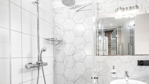 A modern bathroom with a shower, a sink, and a mirror. - RentPlanet - Apartamenty Rybaki (Poznan)