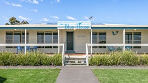 A building named 'The Blue House' with a front porch, a signboard, and a pathway leading to the entrance. - With stunning views, the Blue House is perfect to relax in affordable Luxury.  (Meningie)