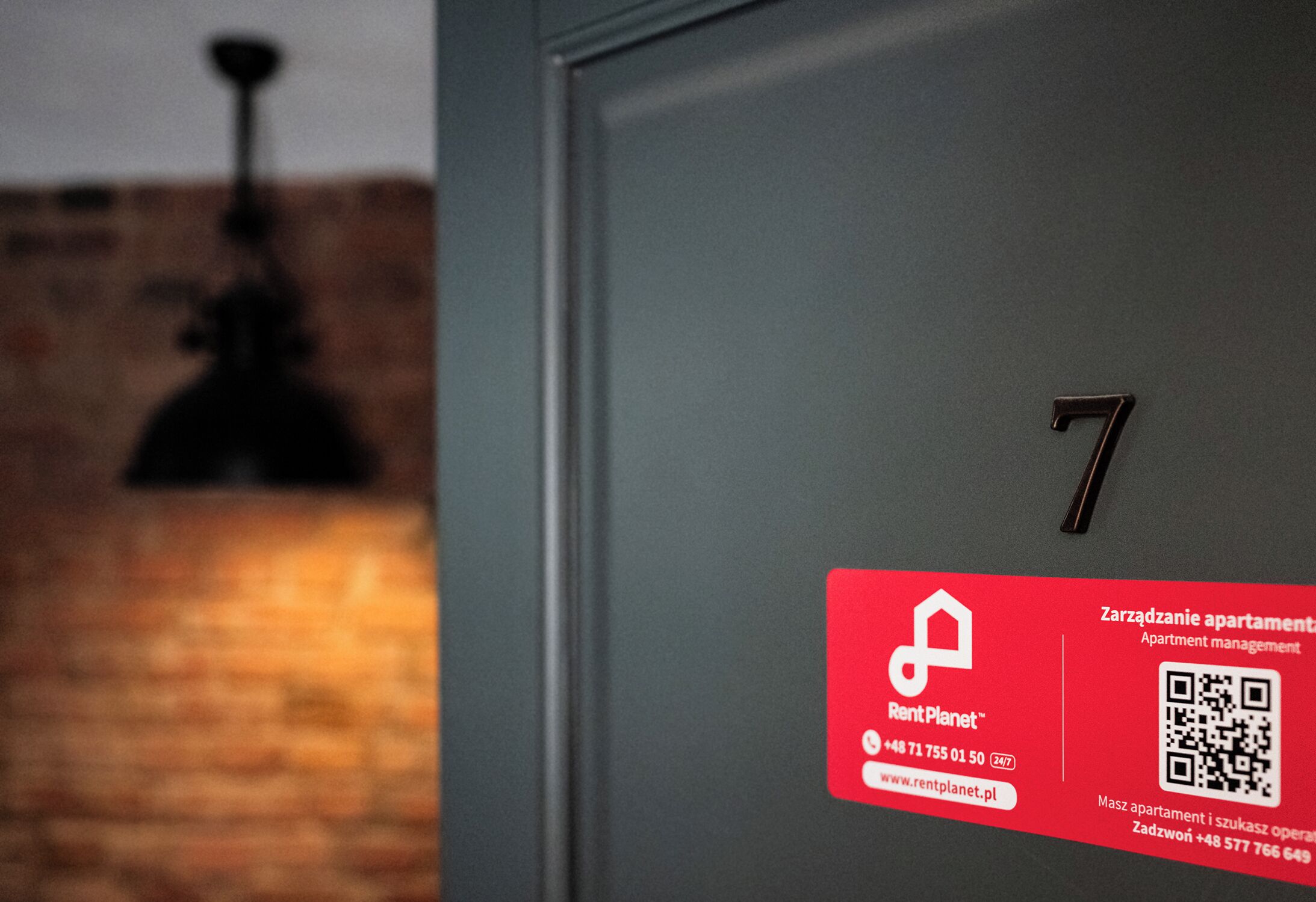 A close-up of a door with a red sign indicating room number 7, a QR code, and contact information for RentPlanet.