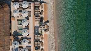 An aerial view of a beachside resort with multiple lounge areas, umbrellas, and a wooden deck. - Folie Marine Beach Hotel & Club (Himare)