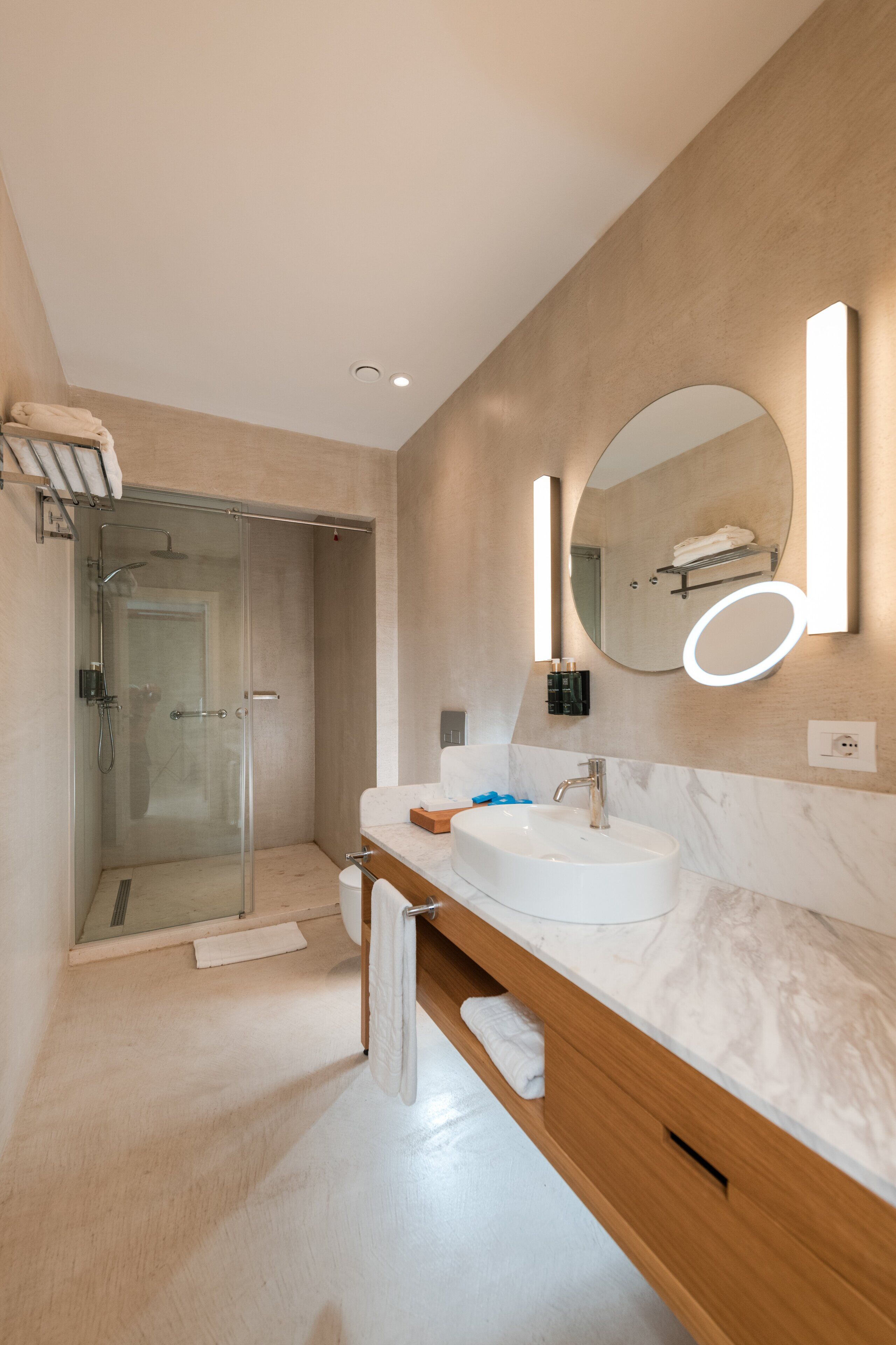 Un baño moderno con cabina de ducha de vidrio, un espejo grande y encimera de mármol.