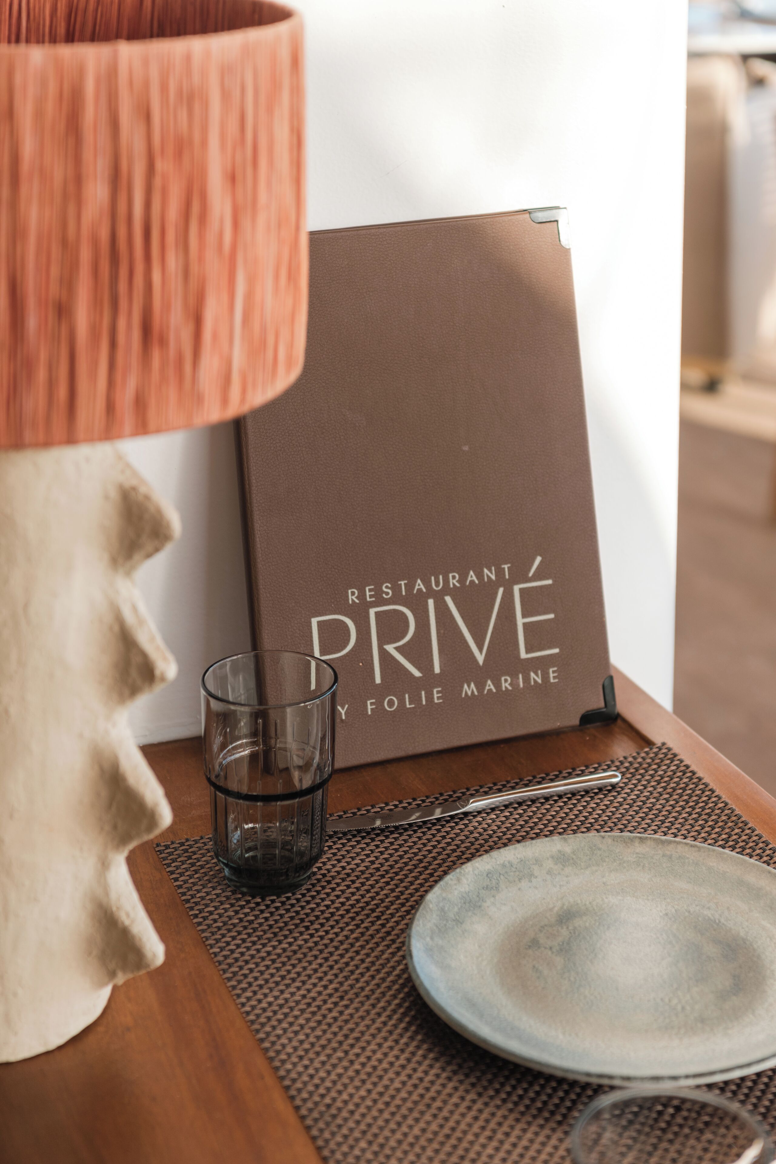A table with a menu, a glass, and a plate.